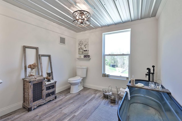 bathroom with toilet, wood finished floors, baseboards, ornamental molding, and visible vents