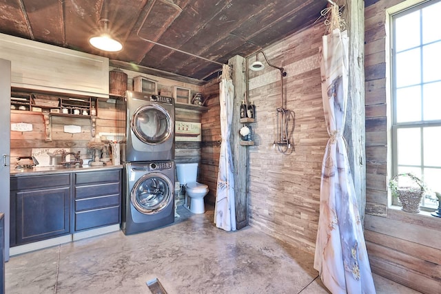 washroom featuring wood ceiling, wooden walls, stacked washer and clothes dryer, and laundry area