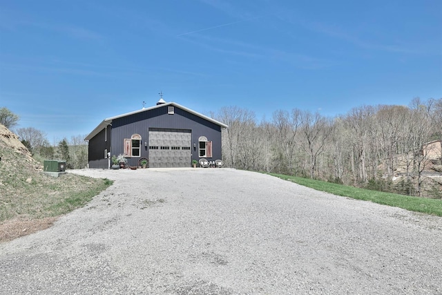 view of side of property featuring a garage, an outbuilding, and gravel driveway