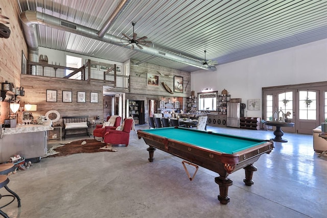 rec room with wooden walls, a high ceiling, finished concrete flooring, and pool table