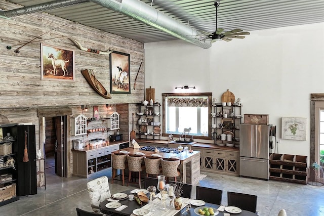 dining area with ceiling fan, concrete flooring, and a high ceiling