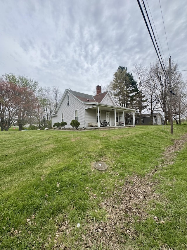exterior space with a lawn, a chimney, and covered porch