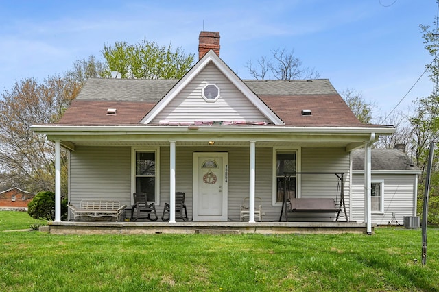 view of front of house with a front lawn, roof with shingles, central AC unit, and covered porch