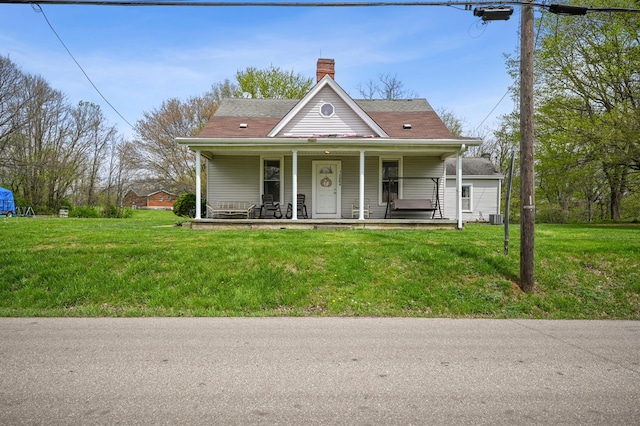 view of front of property with a front lawn, a chimney, covered porch, and central AC