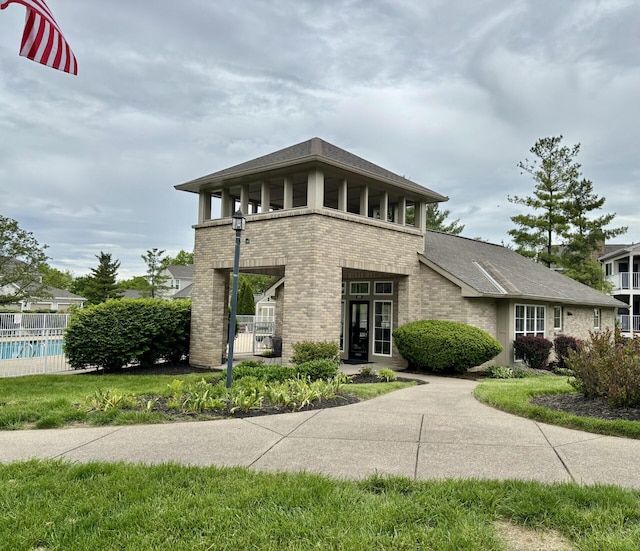 207 S Watchtower Dr Unit 203, Wilder, KY 41076 - view of front facade featuring brick siding, fence, a shingled roof, and a balcony
