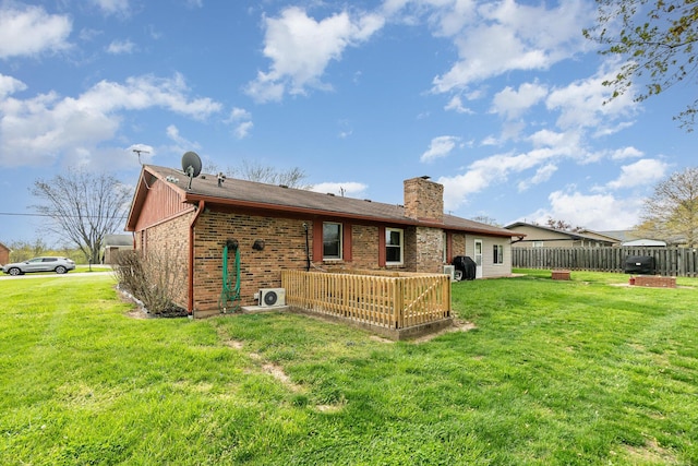 back of property featuring brick siding, a lawn, a chimney, and fence