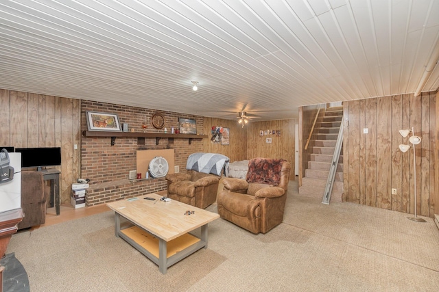 carpeted living room with stairway, ceiling fan, wood ceiling, and wooden walls