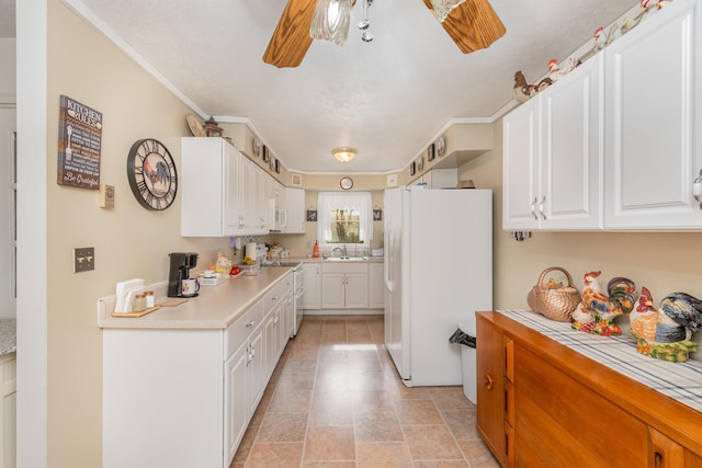 kitchen with white cabinets, a sink, white appliances, ceiling fan, and light countertops
