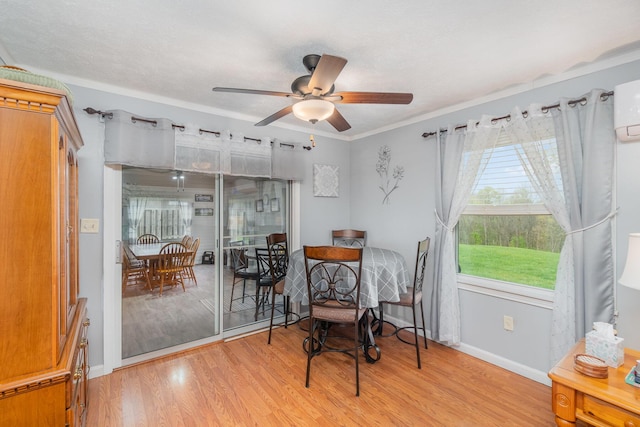 living area with light wood-style floors, a ceiling fan, baseboards, and ornamental molding