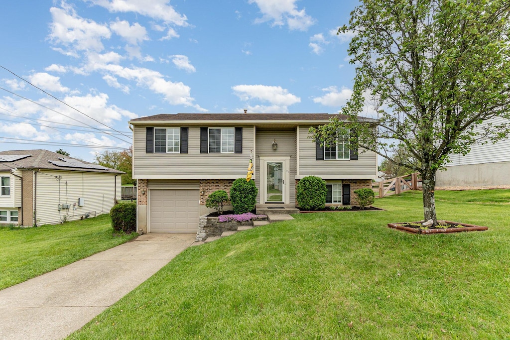 bi-level home with brick siding, a front lawn, and driveway