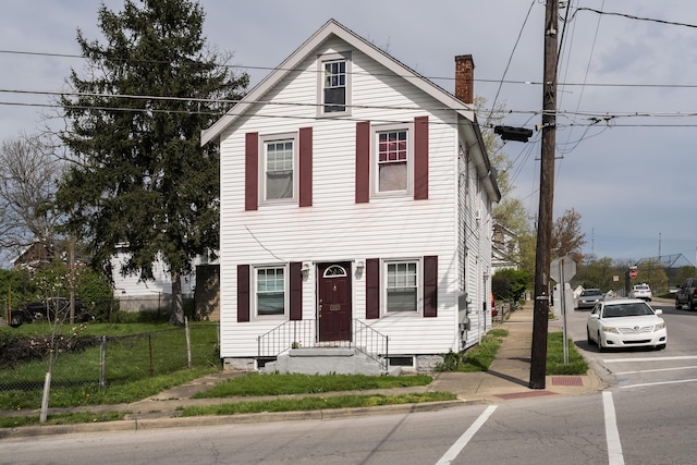 view of front of home with a chimney and fence
