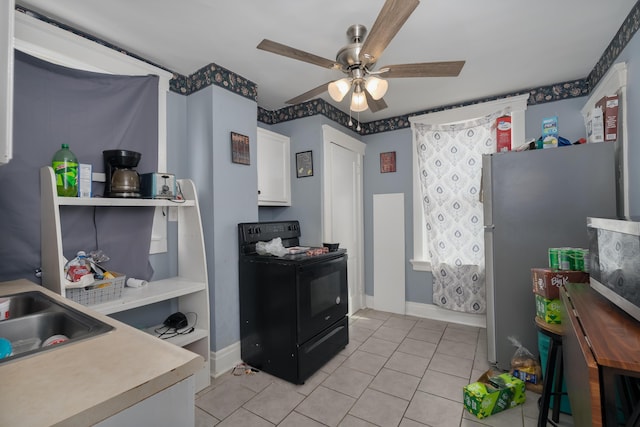 kitchen featuring light tile patterned floors, ceiling fan, white cabinets, black range with electric stovetop, and freestanding refrigerator