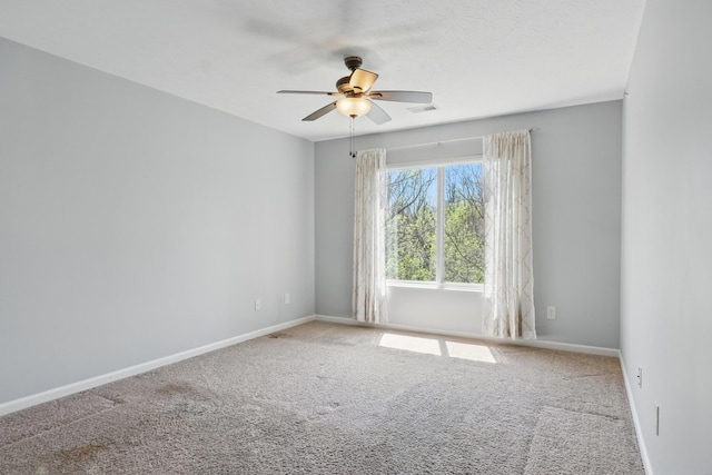 carpeted spare room featuring visible vents, a ceiling fan, and baseboards