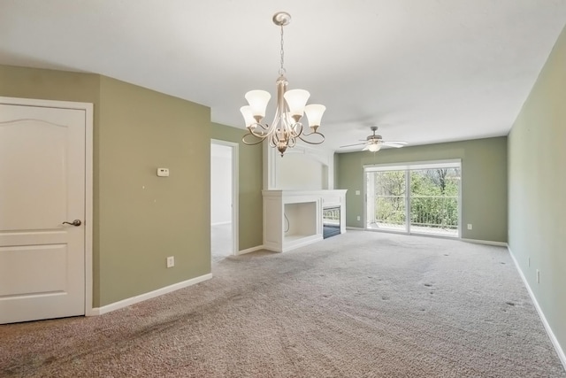 unfurnished living room featuring carpet floors, baseboards, ceiling fan with notable chandelier, and a fireplace