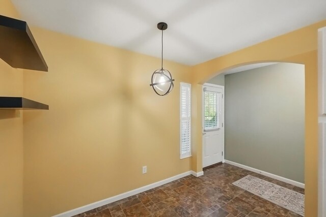 interior space featuring arched walkways, baseboards, and stone finish floor