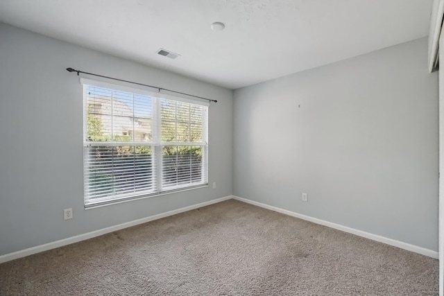 carpeted empty room featuring baseboards and visible vents
