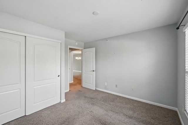unfurnished bedroom featuring carpet floors, baseboards, and a closet