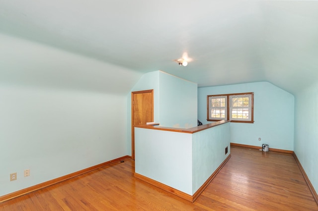 bonus room with baseboards, vaulted ceiling, and light wood-type flooring