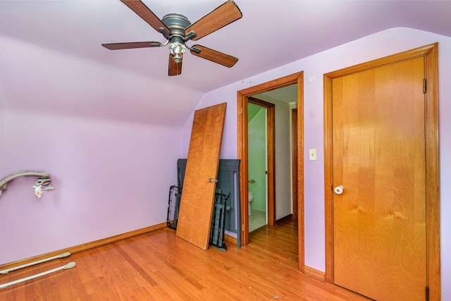 spare room featuring baseboards, ceiling fan, light wood-style flooring, and lofted ceiling