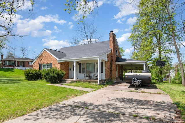 view of front of property with a front lawn, a chimney, brick siding, concrete driveway, and a porch