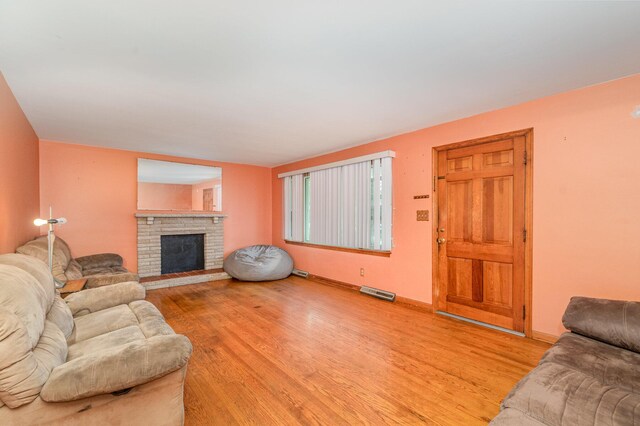 living area featuring baseboards, a fireplace, light wood-type flooring, and visible vents