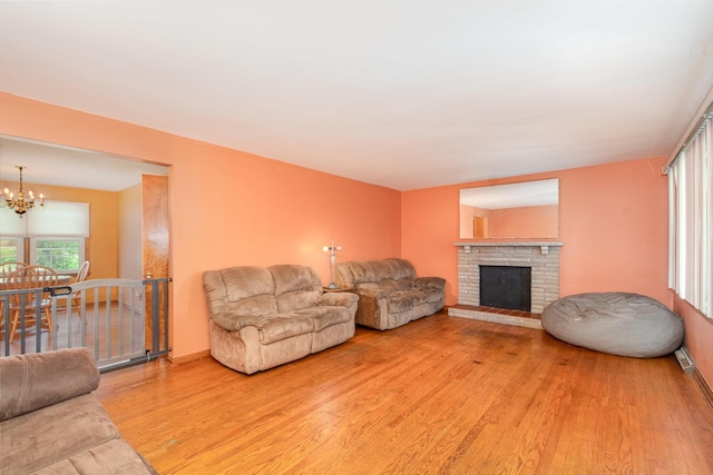 living area with an inviting chandelier, baseboards, wood finished floors, and a fireplace