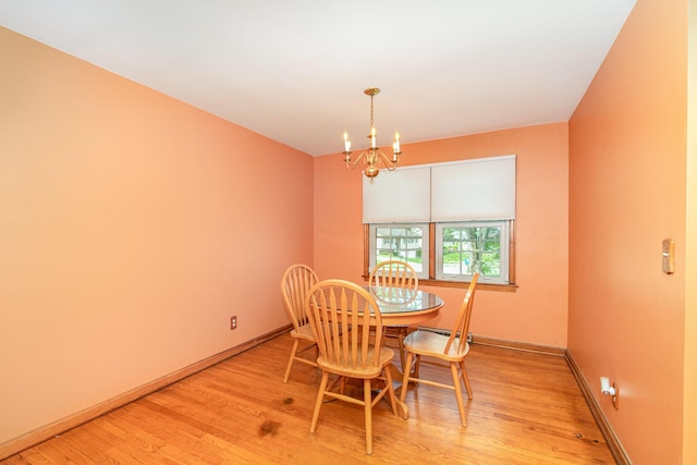 dining area with baseboards, an inviting chandelier, and light wood-type flooring