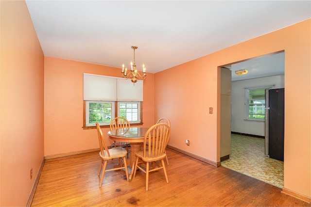 dining room featuring an inviting chandelier, light wood finished floors, and baseboards