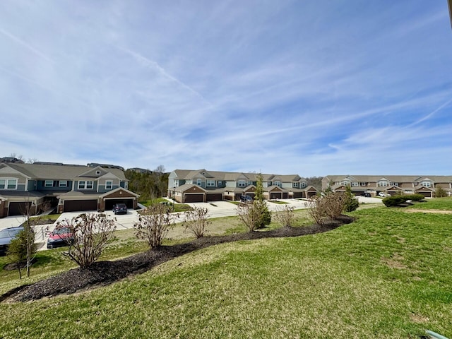 view of yard with a residential view, an attached garage, and driveway
