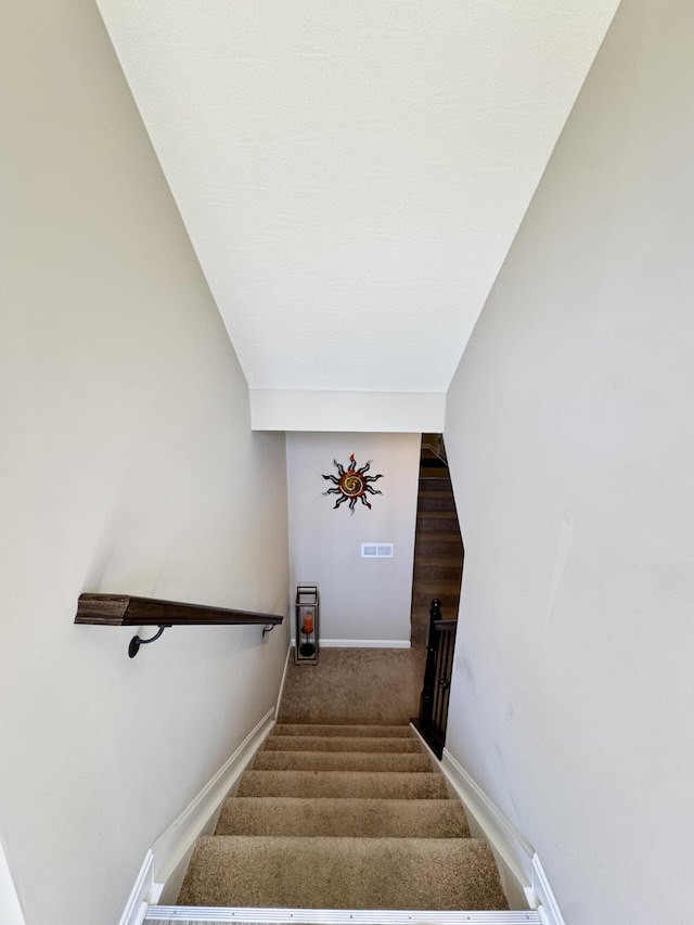 staircase with baseboards, visible vents, and carpet floors