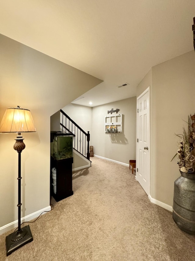 basement featuring stairway, carpet floors, baseboards, and visible vents