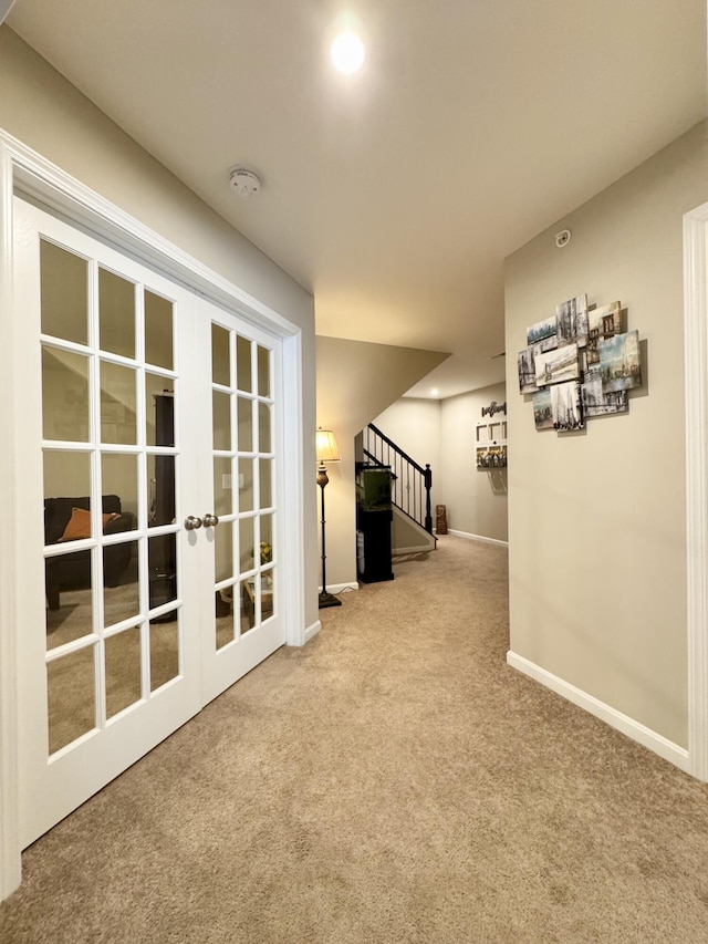 hall with baseboards, french doors, carpet flooring, and stairway