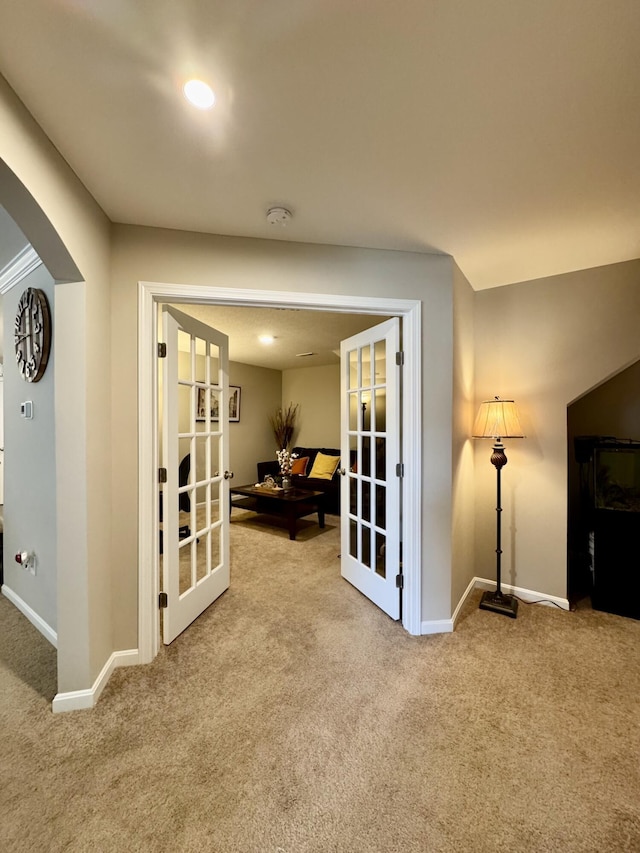 hall featuring arched walkways, carpet flooring, french doors, and baseboards