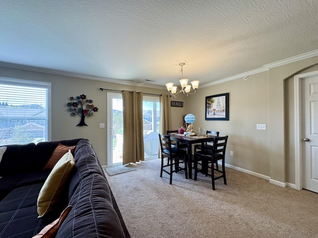 carpeted dining space featuring a notable chandelier, a textured ceiling, arched walkways, baseboards, and ornamental molding