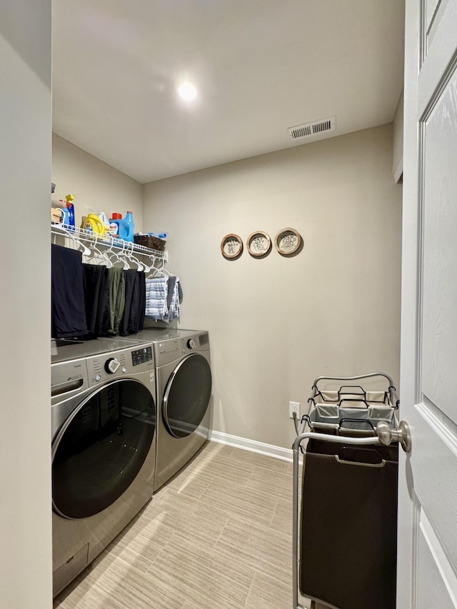 laundry area featuring baseboards, visible vents, washer and clothes dryer, and laundry area