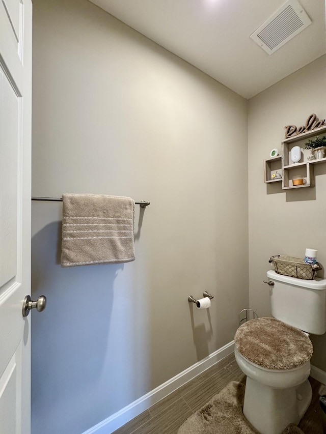 bathroom with wood finished floors, visible vents, toilet, and baseboards