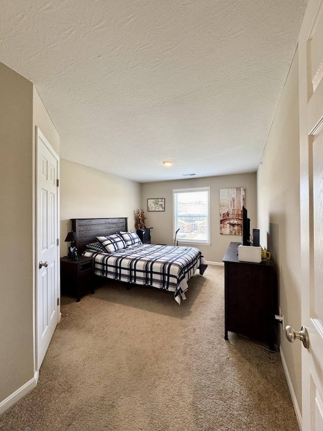 bedroom featuring visible vents, baseboards, carpet, and a textured ceiling