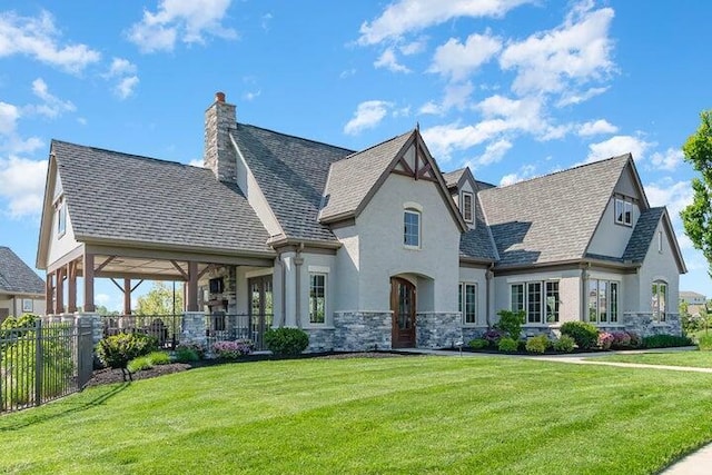 view of front of property with stucco siding, fence, stone siding, and a front yard