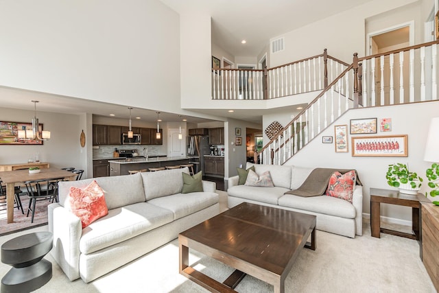 living area featuring recessed lighting, a high ceiling, an inviting chandelier, visible vents, and baseboards