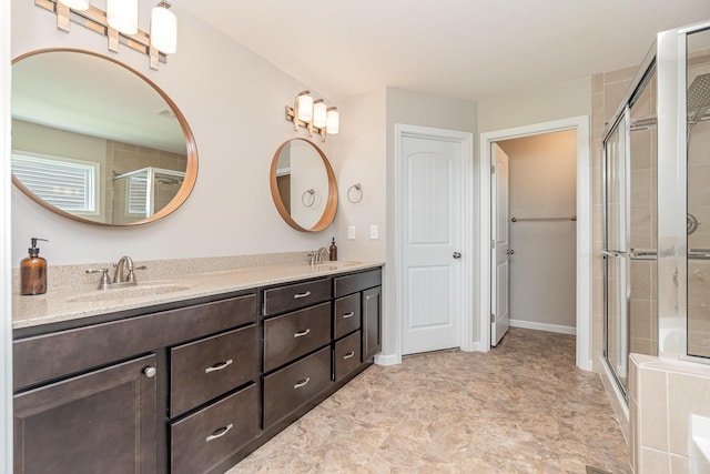 full bathroom featuring double vanity, a stall shower, and a sink