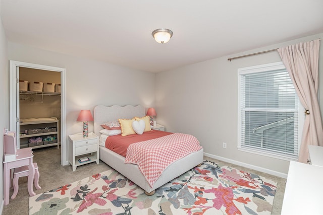 bedroom with a closet, carpet flooring, baseboards, and a walk in closet