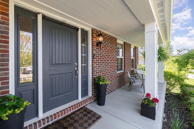 entrance to property featuring covered porch and brick siding