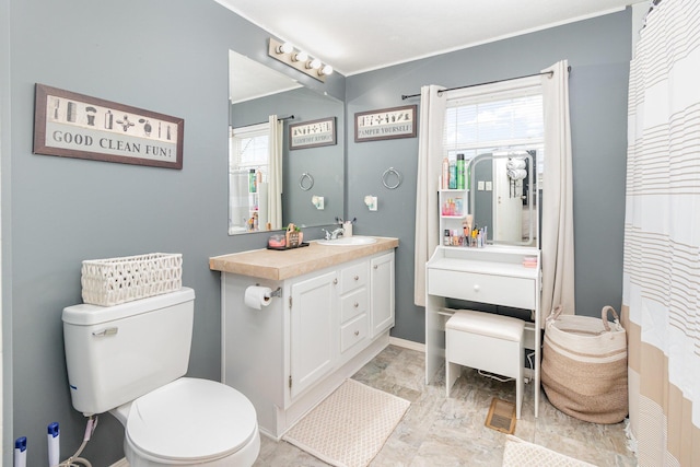 bathroom featuring plenty of natural light, vanity, ornamental molding, and toilet