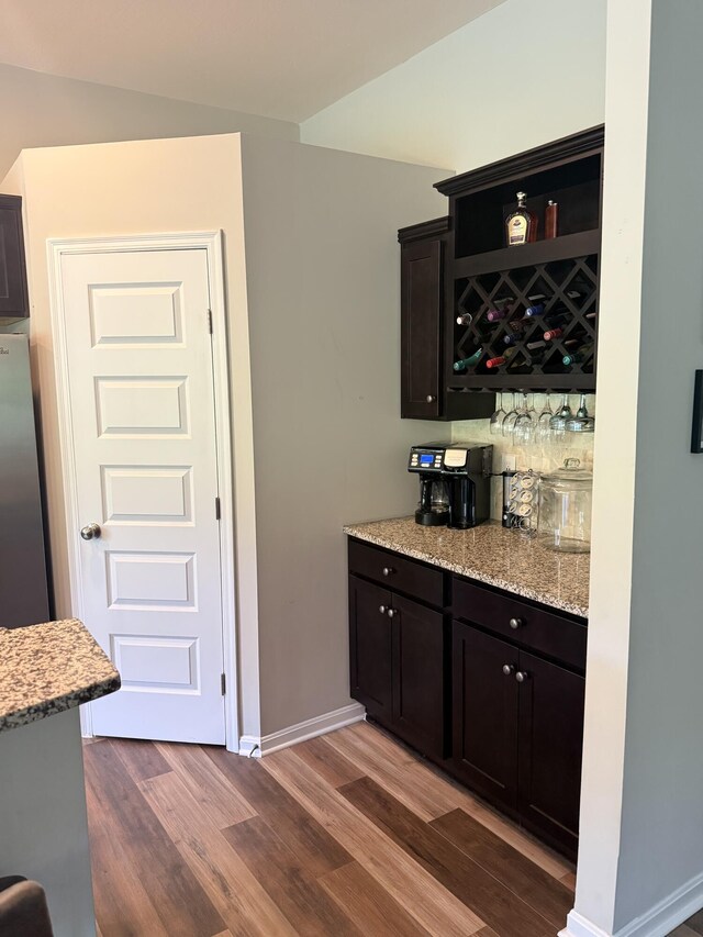 bar featuring baseboards, a dry bar, dark wood-type flooring, and freestanding refrigerator