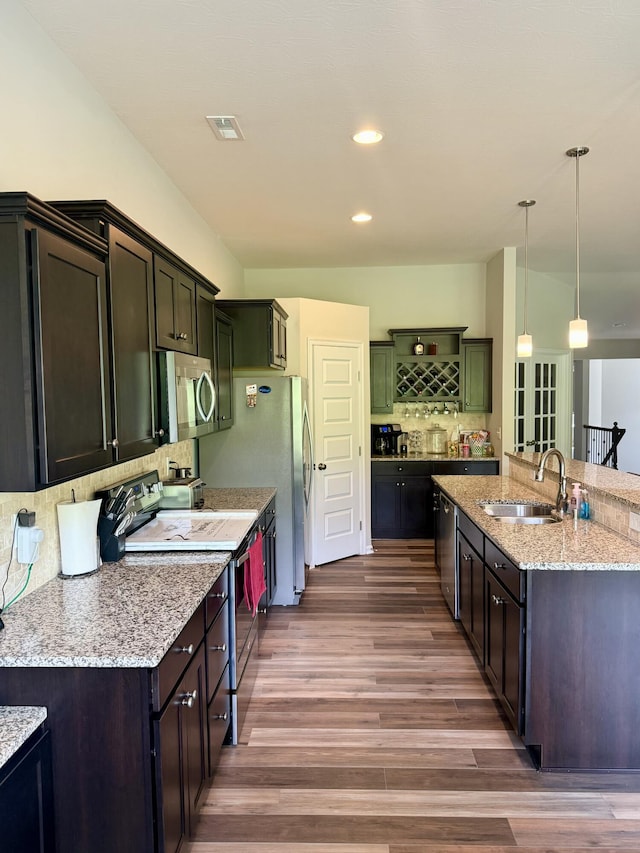 kitchen with dark wood-style floors, backsplash, visible vents, a sink, and appliances with stainless steel finishes