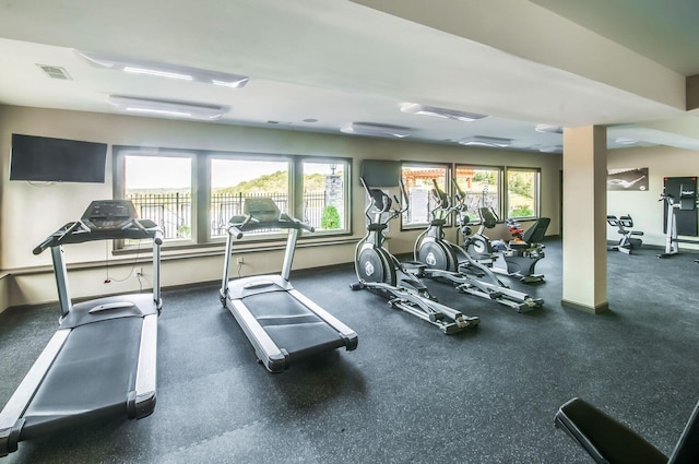 gym featuring visible vents, baseboards, and a healthy amount of sunlight
