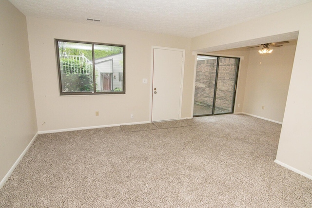 spare room featuring visible vents, carpet flooring, a textured ceiling, and baseboards
