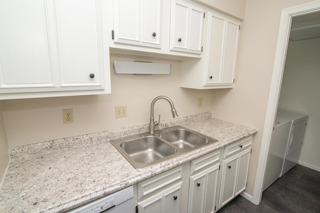 kitchen with a sink, independent washer and dryer, and white cabinetry