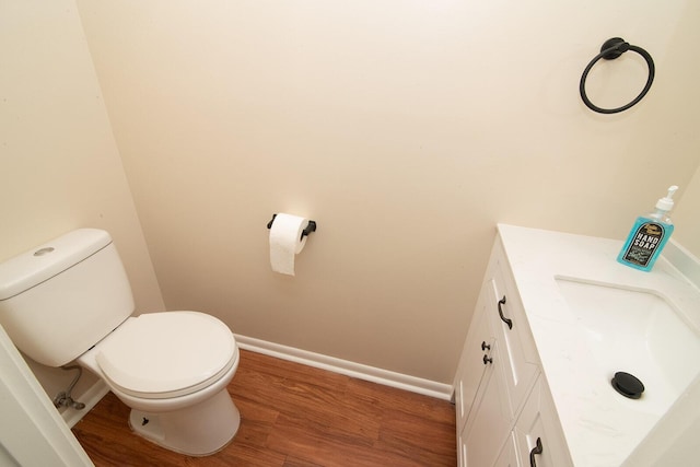 bathroom with baseboards, vanity, toilet, and wood finished floors