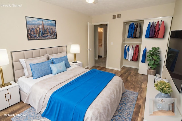 bedroom featuring baseboards, visible vents, wood finished floors, and a closet